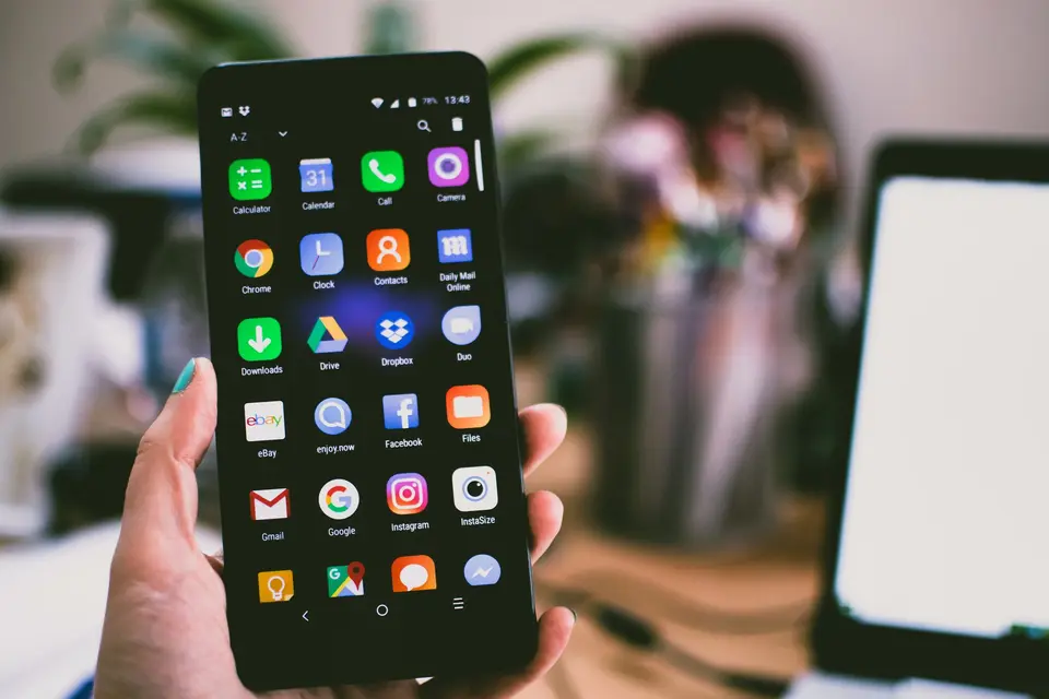Hand hält ein Smartphone mit App-Symbolen auf dem Startbildschirm