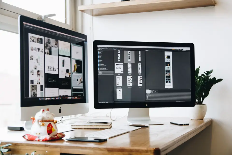 Zwei Bildschirme mit Layout-Entwürfen auf einem Schreibtisch