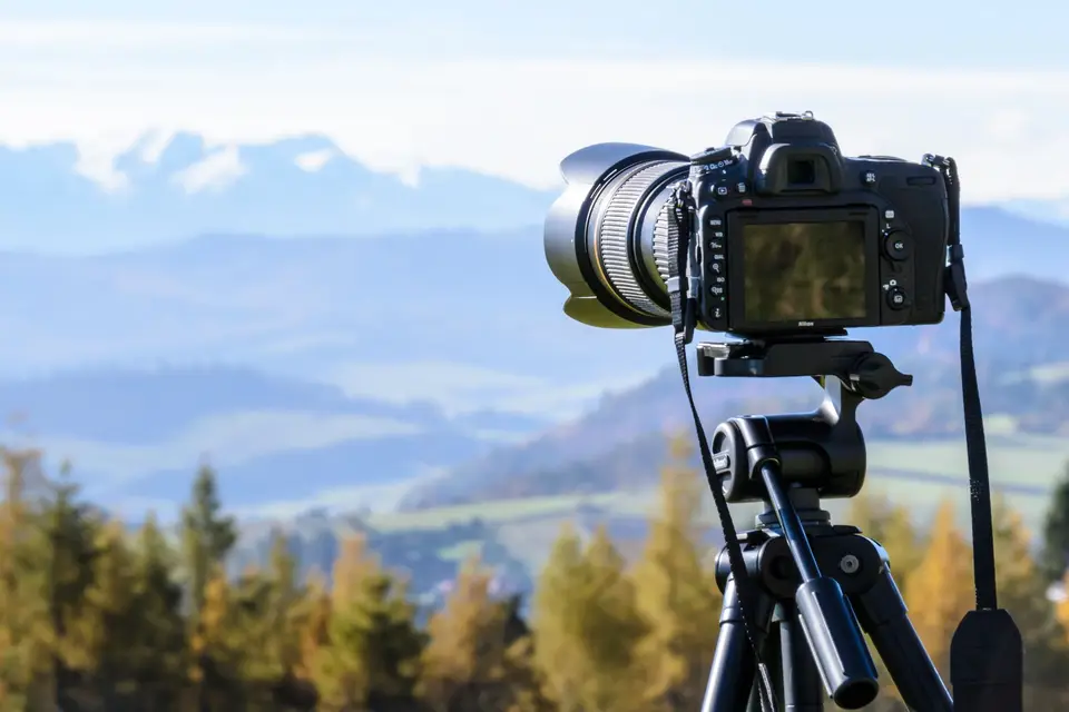 Spiegelreflexkamera auf einem Stativ vor einer Berglandschaft