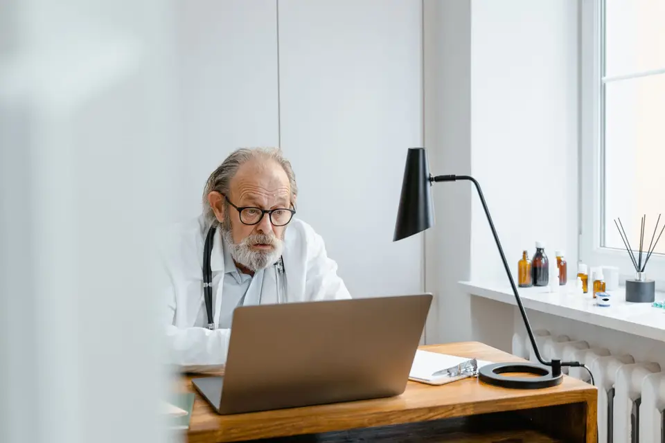 Arzt im Kittel arbeitet am Laptop in seiner Praxis