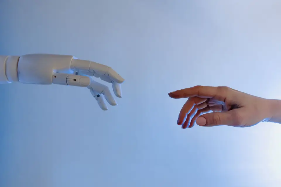 Roboterhand und menschliche Hand nähern sich vor blauem Hintergrund