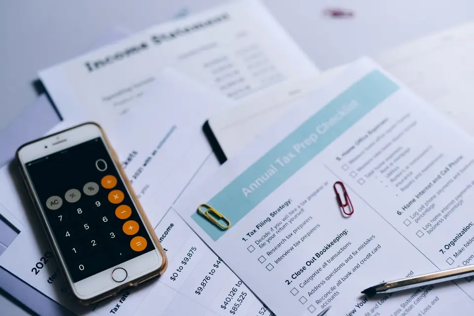 Smartphone mit Taschenrechner liegt auf Buchhaltungsunterlagen