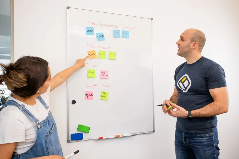 Zwei Personen planen mit bunten Haftnotizen an einem Whiteboard