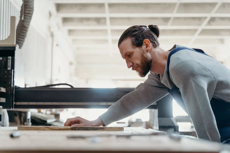 Tischler arbeitet an einer Maschine in einer hellen Werkstatt