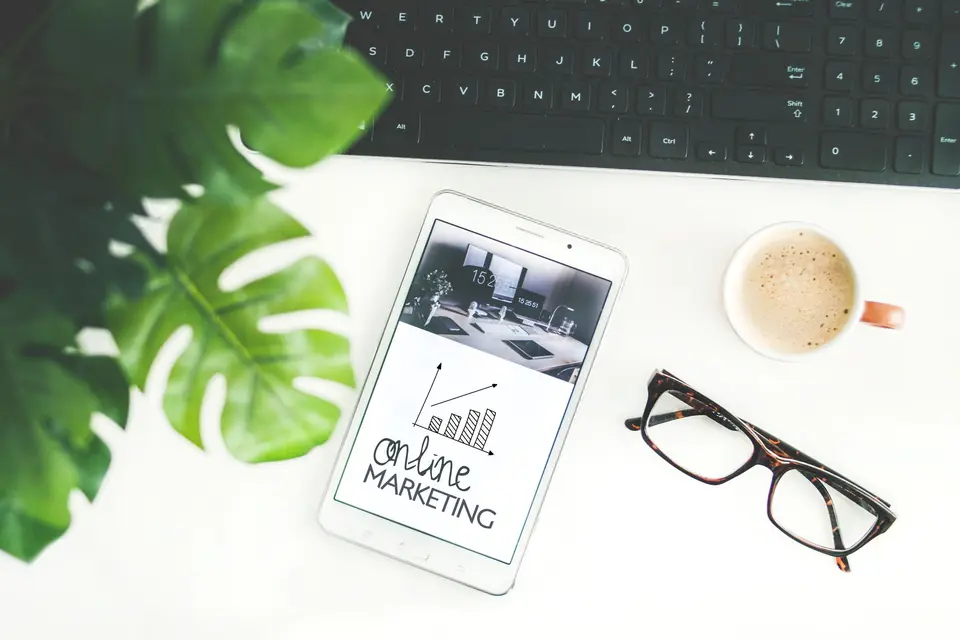 Tablet mit der Skizze „Online Marketing“ neben Kaffee, Brille und Tastatur